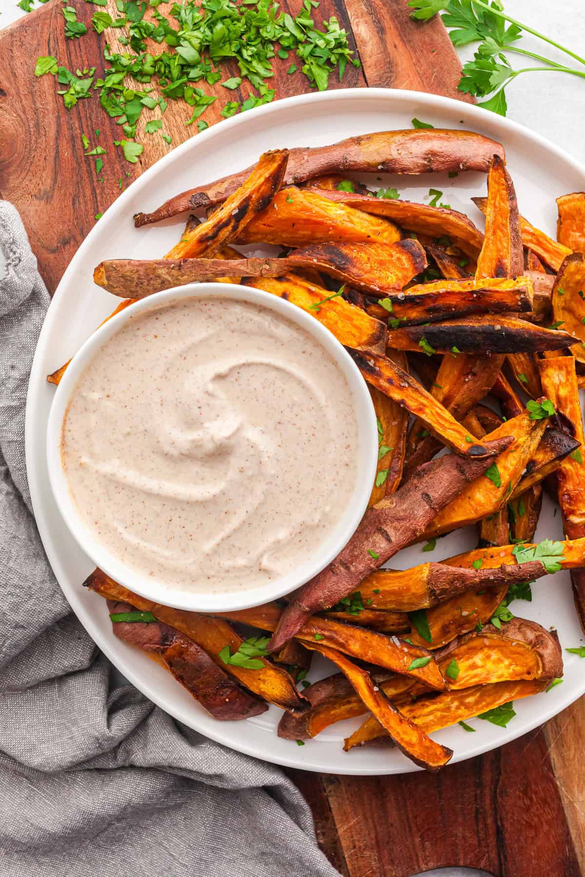 roasted sweet potato on a plate with a bowl of yogurt dipping sauce. 