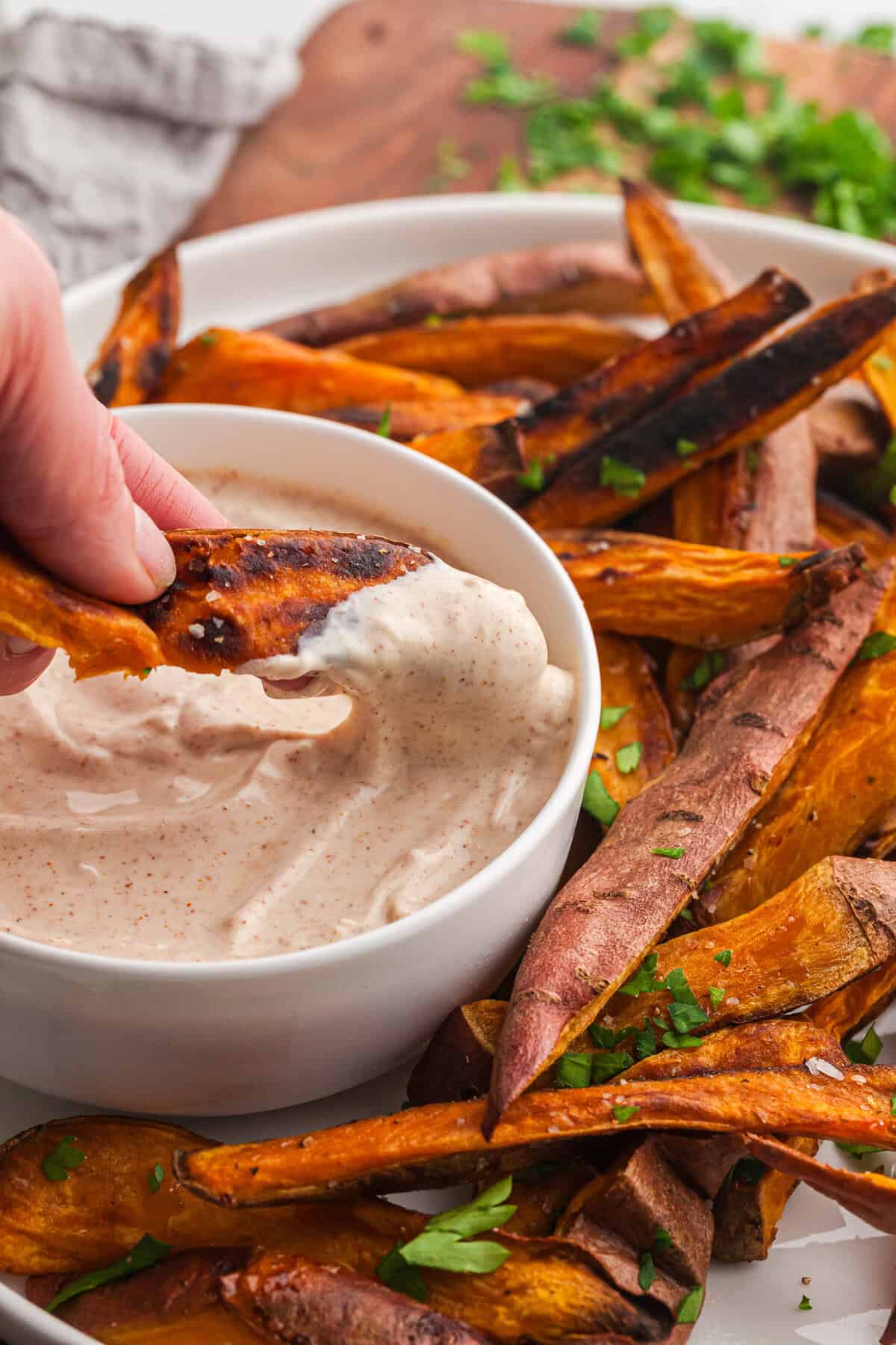 a sweet potato being dips in to a yogurt sauce