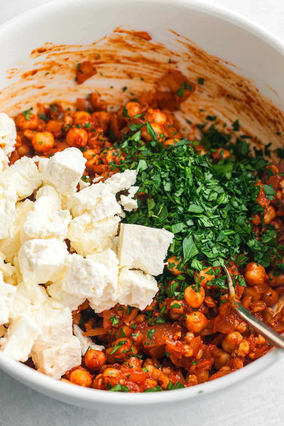 feta and parsley being folding in to the chickpeas mixture. 