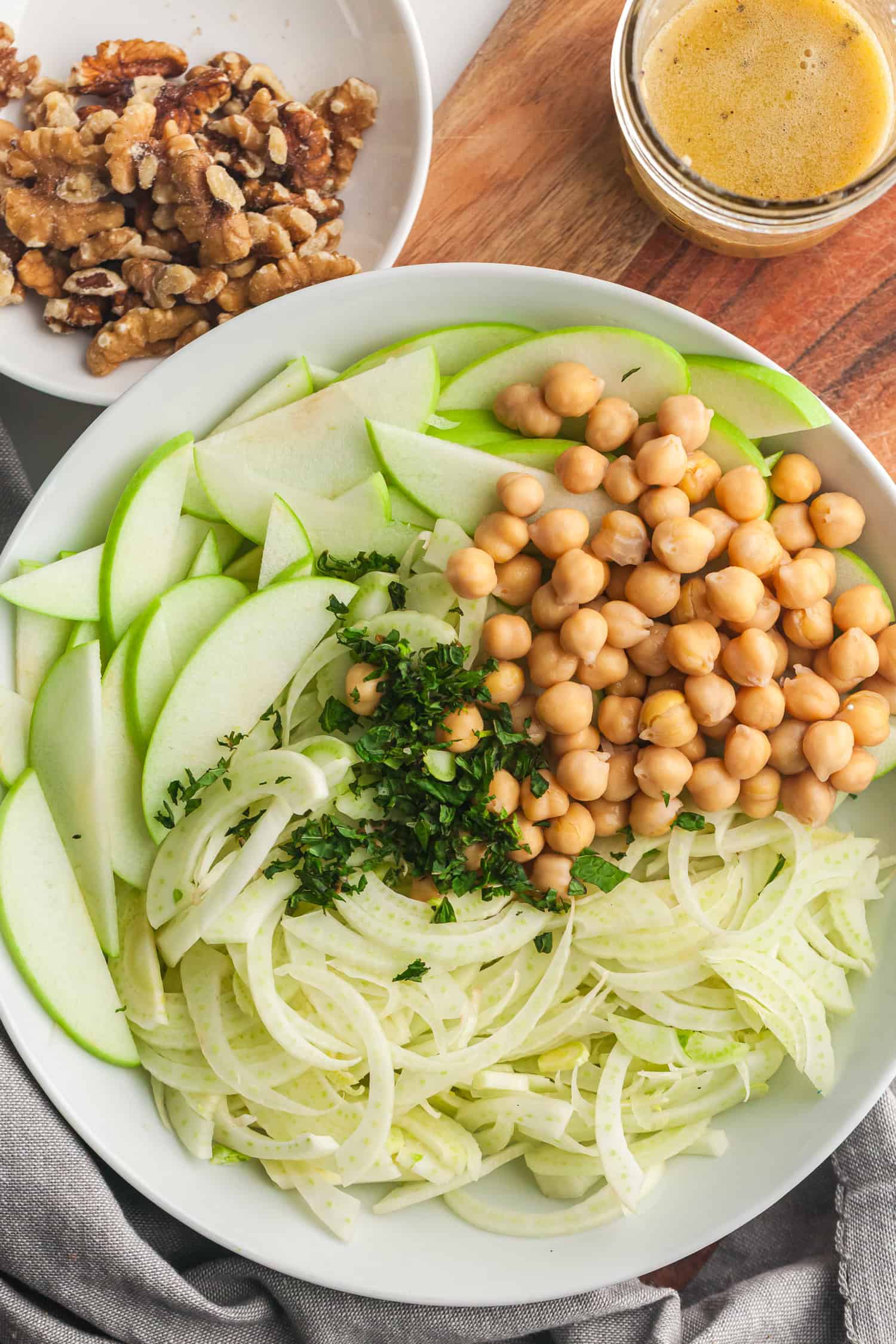Apple fennel slaw served in a bowl with chickpeas, walnuts, and fresh herbs.