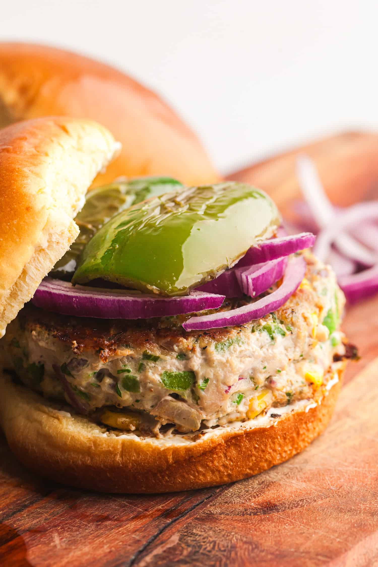 Grilled jalapeño turkey burger with cheddar, red onion, and green bell pepper on a toasted bun, ready to serve.