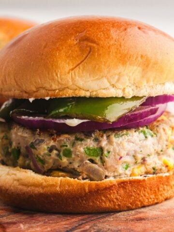 Grilled turkey burger with cheddar cheese, jalapeños, red onion, and green bell pepper on a toasted bun.