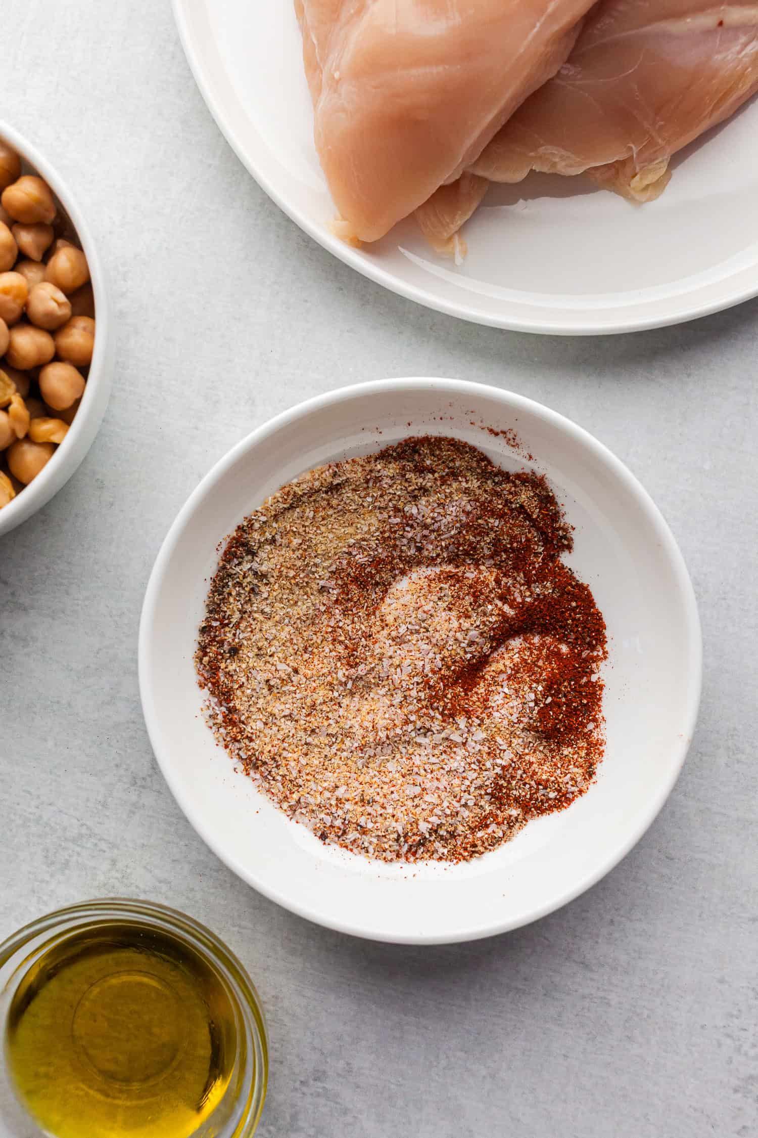 Seasoning mix with raw chicken, chickpeas, and olive oil ready for kale and chicken salad