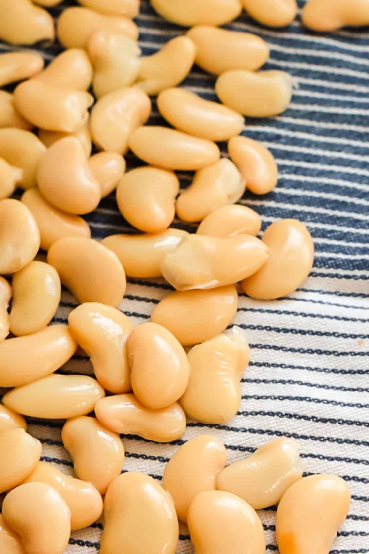 A pile of smooth, creamy butter beans resting on a blue and white striped kitchen towel.