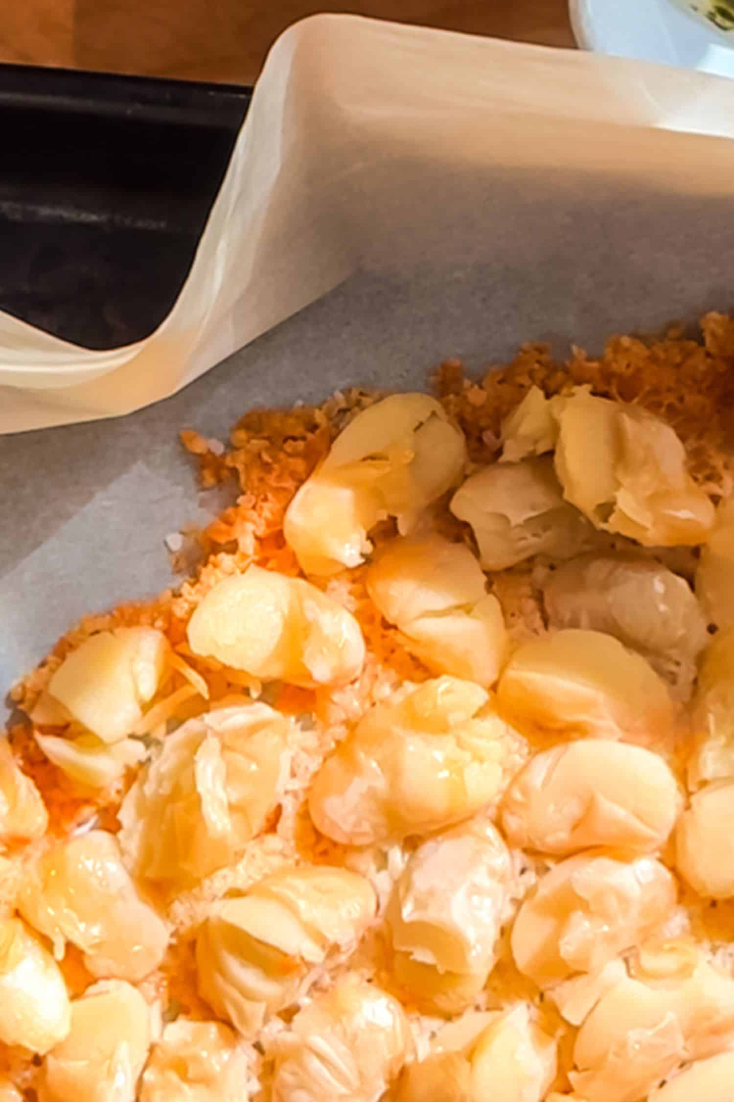 A close-up shot of golden-brown butter beans being roasted on a parchment-lined baking sheet until crispy.