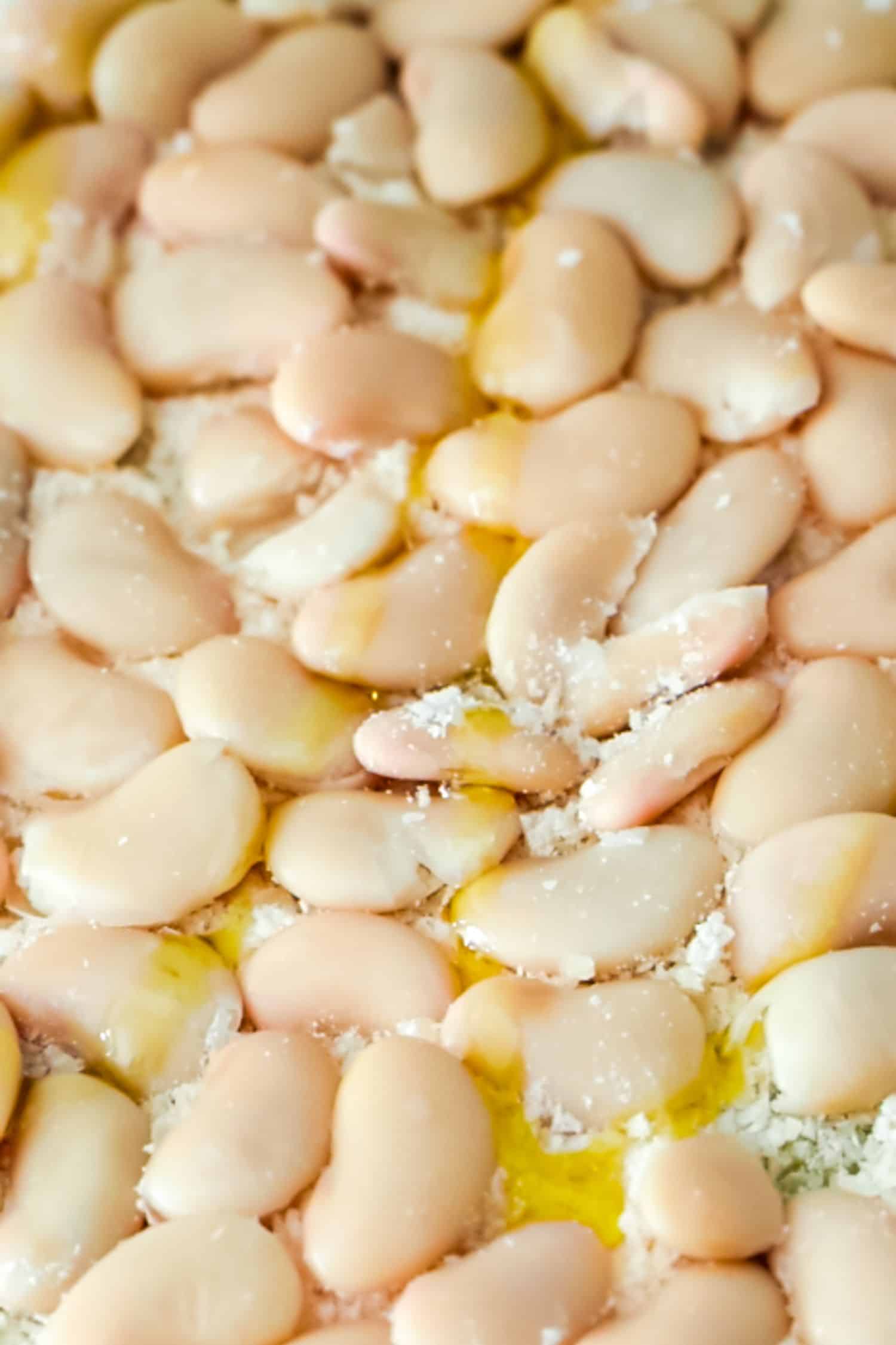 A collection of plump, cooked butter beans drying on a blue and white striped kitchen towel.