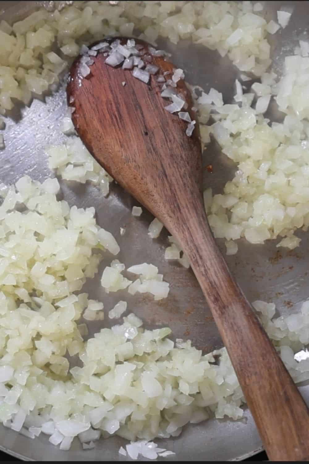 Various cooking ingredients including black beans, an onion, a lime, and spices are arranged on a grey surface.